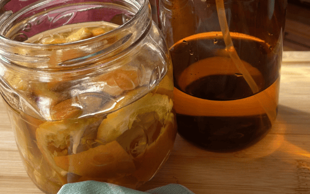 Selbst gemachter Orangenreiniger mit Orangenschalen in einer Glasflasche