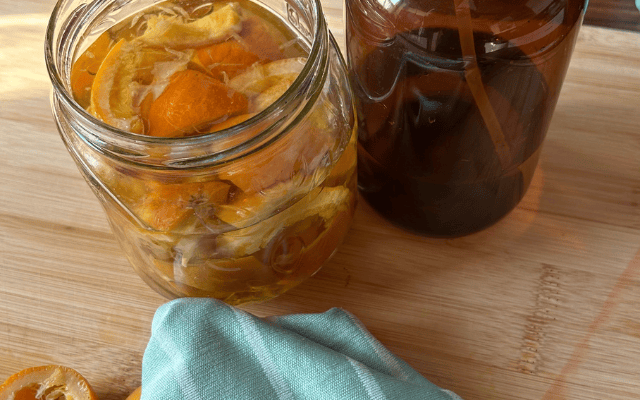 Selbst gemachter Orangenreiniger mit Orangenschalen in einer Glasflasche